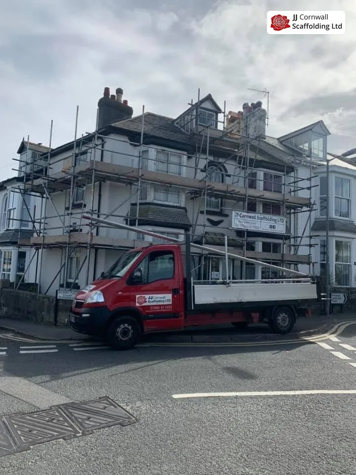 JJ Cornwall Scaffolding: red branded tipper outside a scaffolded terrace