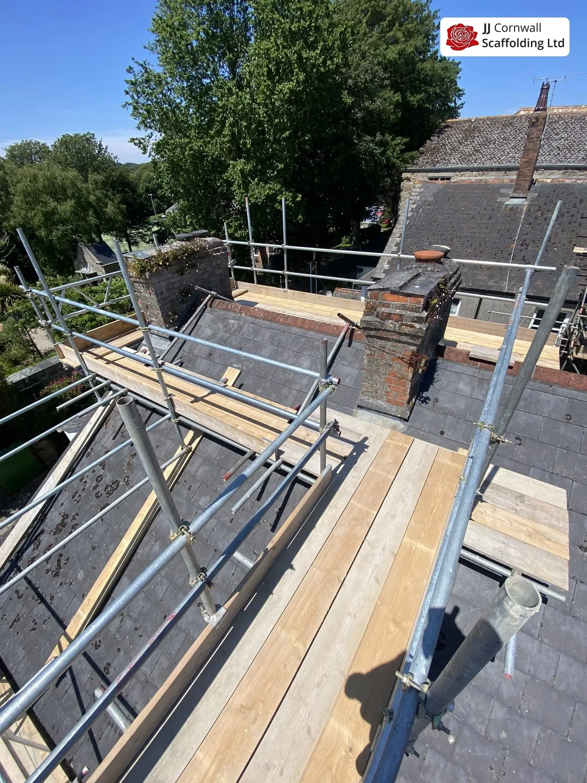 Chimney scaffolding in Cornwall: boarded roof level deck over slate beside a chimney
