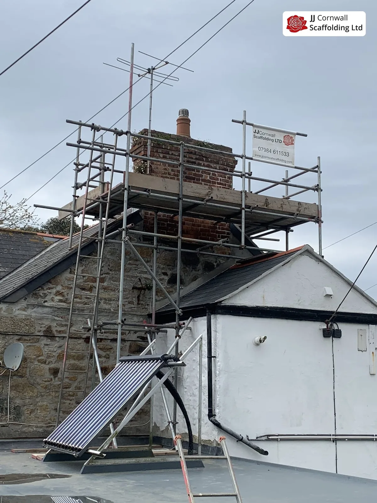 Chimney scaffolding in Cornwall: chimney stack tower off a flat roof beside solar panel