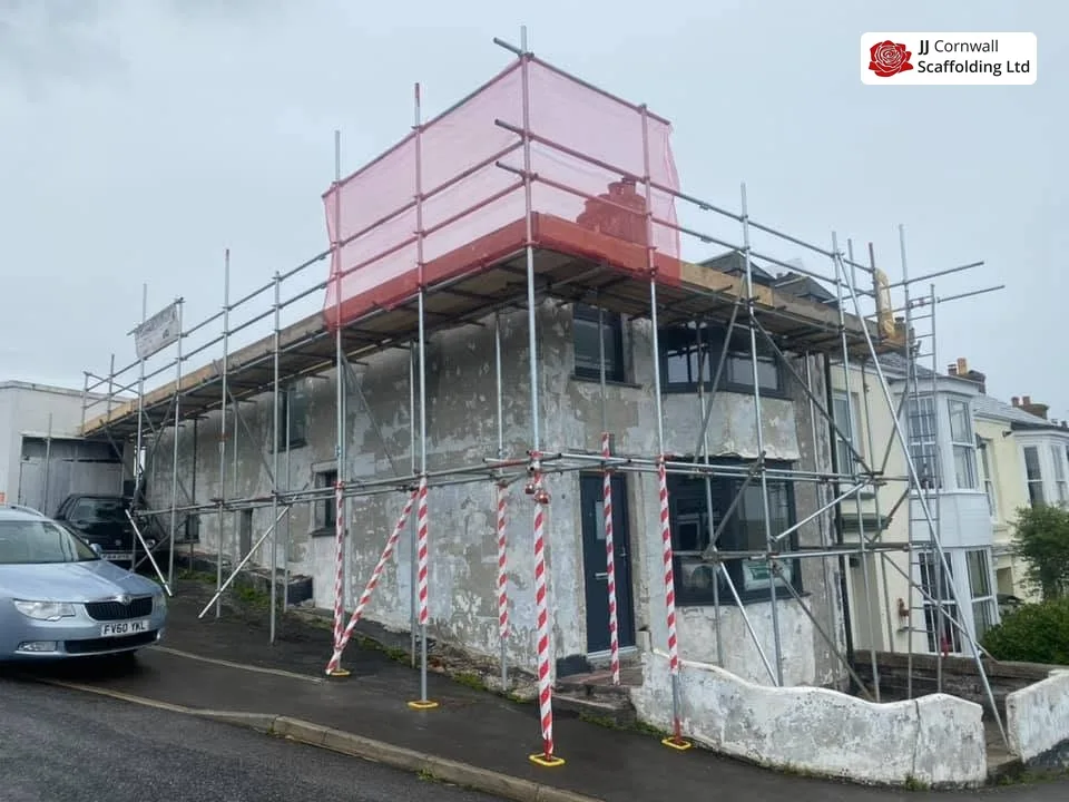 Commercial scaffolding in Cornwall: corner building top lift with red debris netting