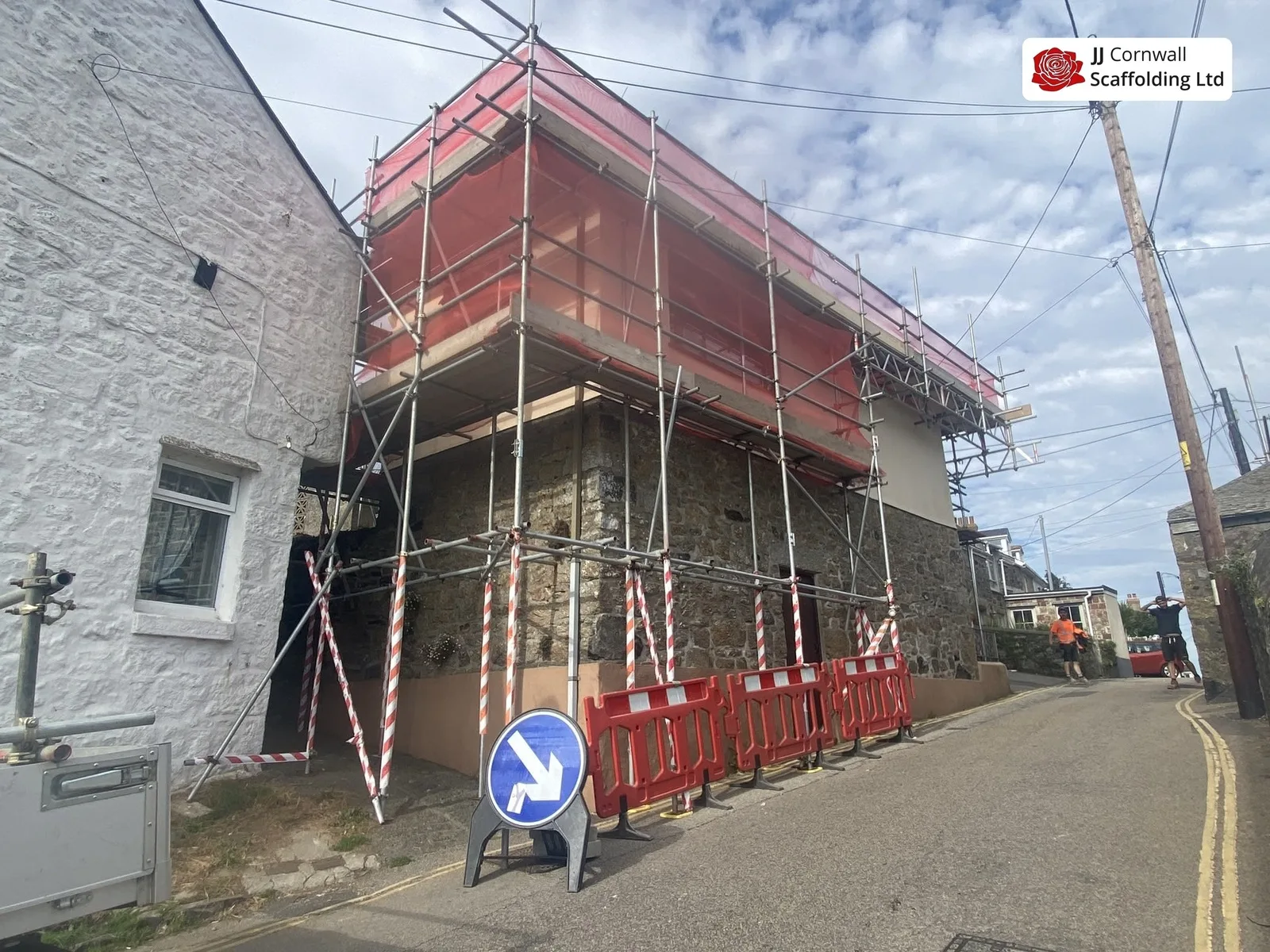 Commercial scaffolding in Cornwall: granite frontage red netting with barriers and diversion sign