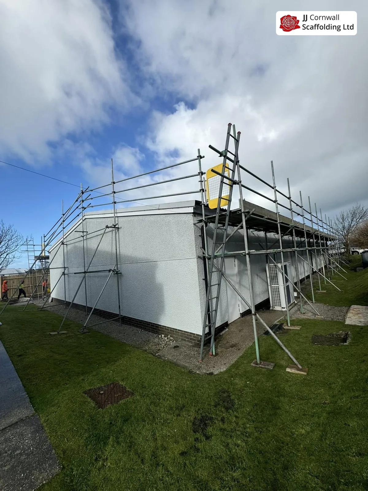 Commercial scaffolding in Cornwall: white clad unit independent scaffold over grass