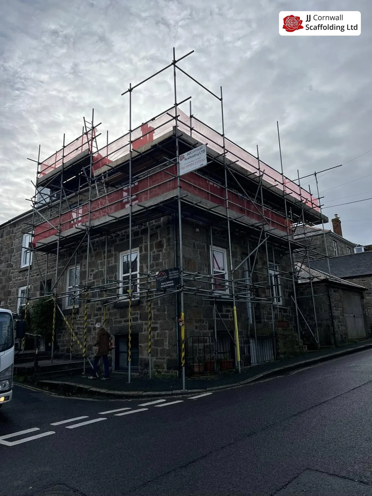 Domestic scaffolding in Cornwall: granite corner building red sheeted top lift junction