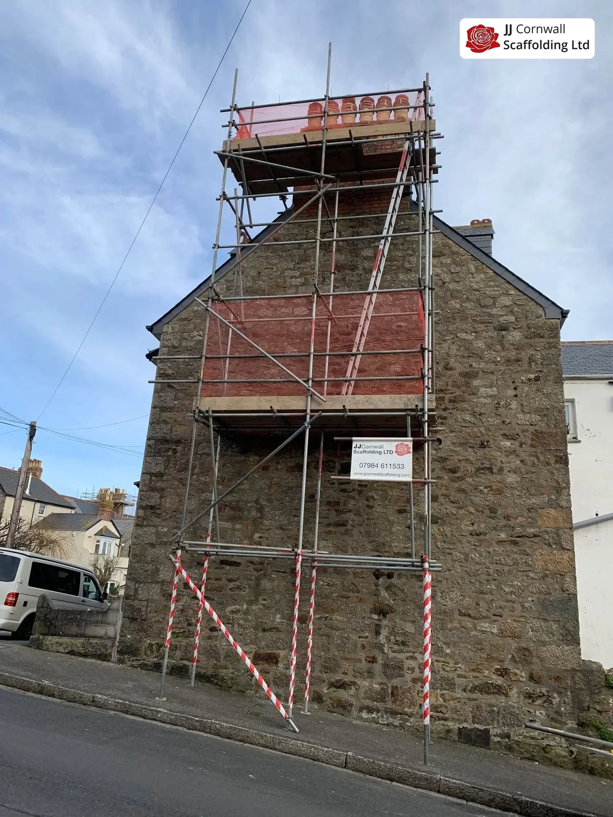 Domestic scaffolding in Cornwall: granite gable end red sheeted top lift street barriers