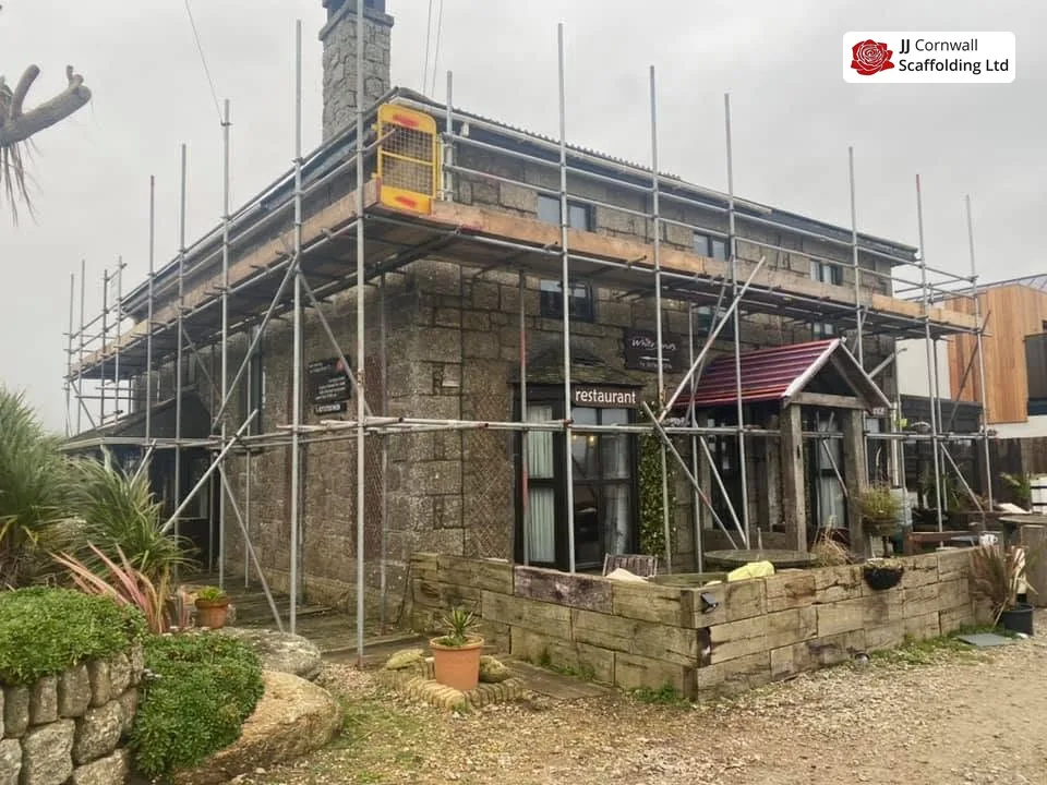 Domestic scaffolding in Cornwall: granite restaurant and terrace roof edge run over the garden