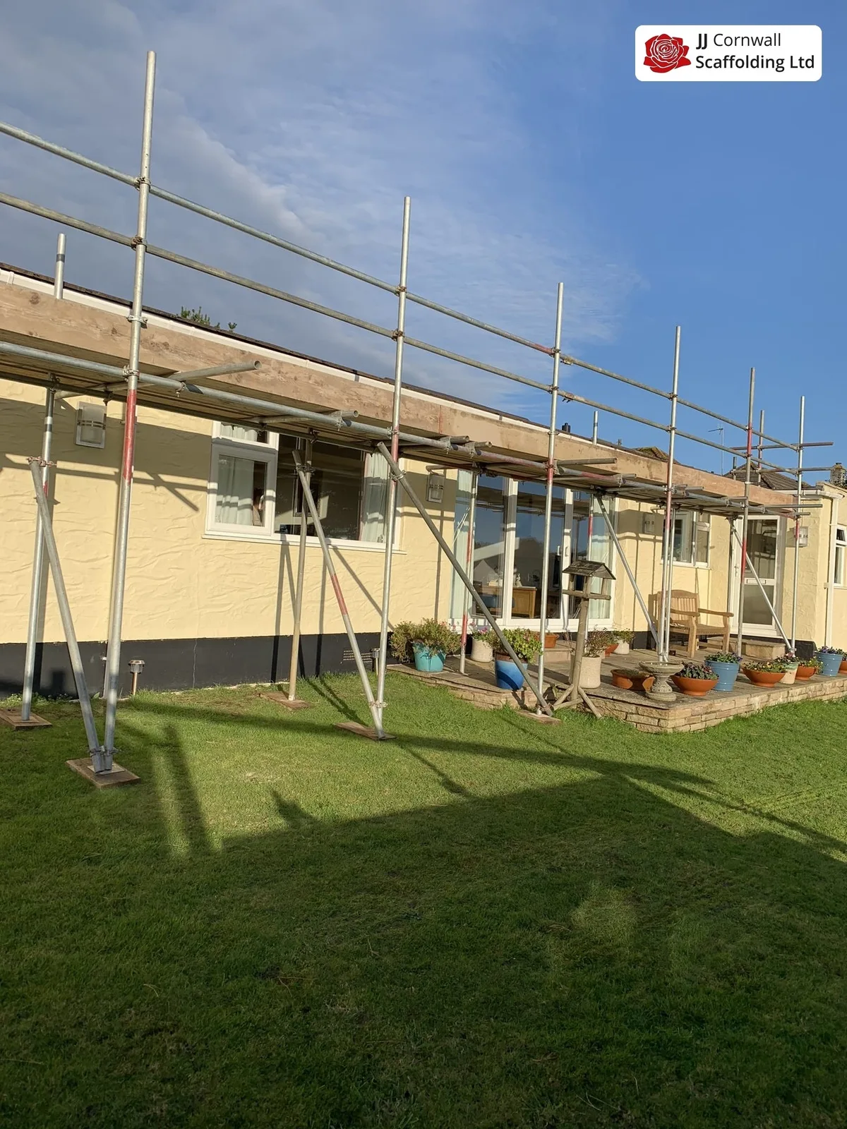 Domestic scaffolding in Cornwall: long cream bungalow wide roof edge scaffold