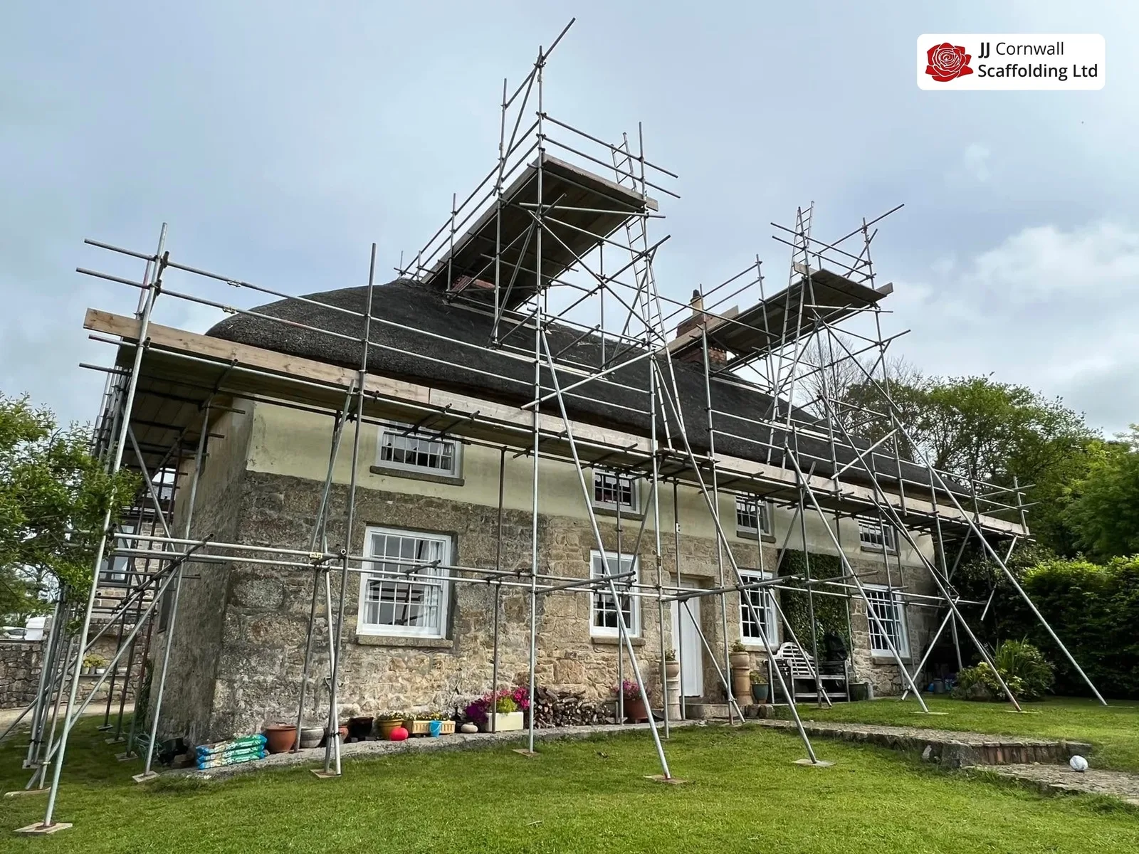 Domestic scaffolding in Cornwall: long granite cottage roof level run from the back lawn