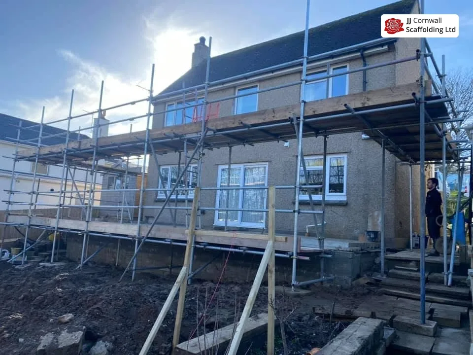 Domestic scaffolding in Cornwall: long rendered elevation two lift scaffold over a dug out site
