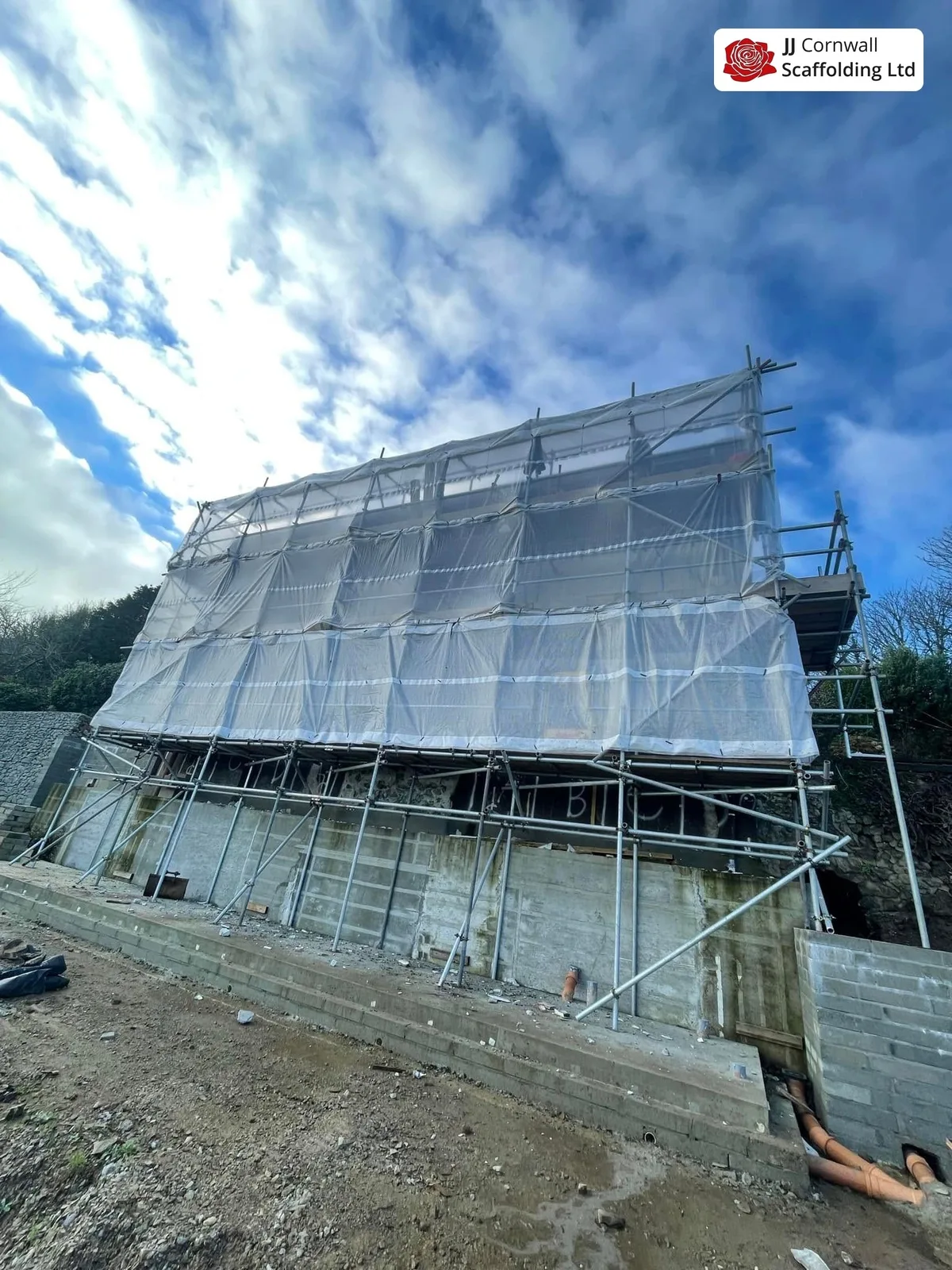 Domestic scaffolding in Cornwall: sheeted scaffold over blockwork shell sloping site