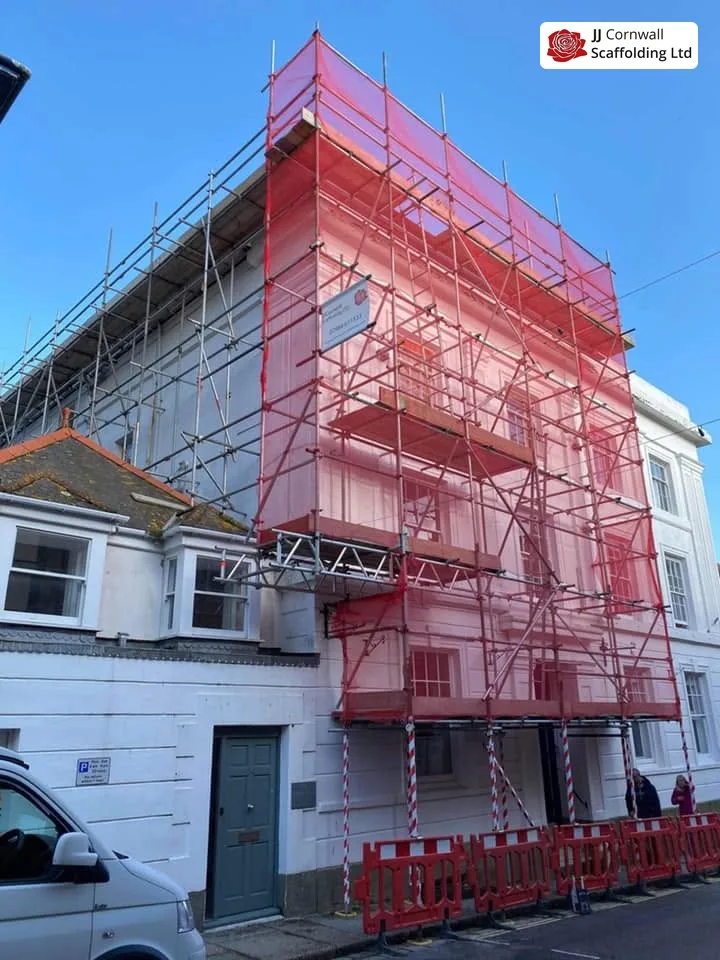Domestic scaffolding in Cornwall: tall terrace full height red debris netting from the street
