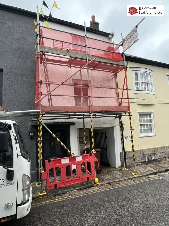 Domestic scaffolding in Cornwall: terrace frontage red netted lift with branded truck and barriers