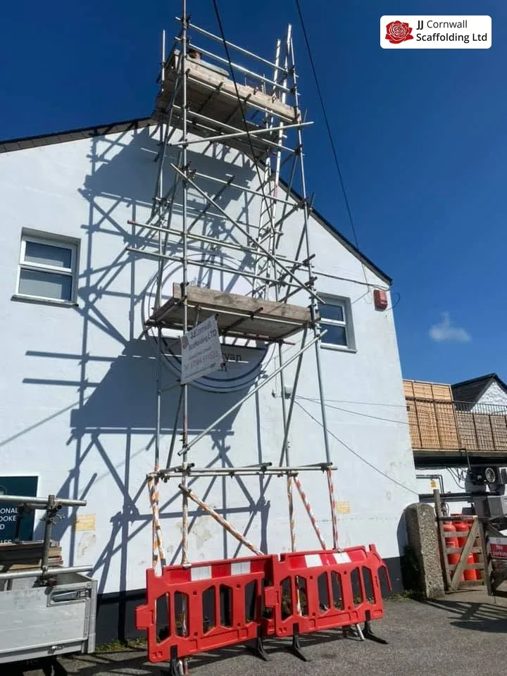 Domestic scaffolding in Cornwall: white gable tall tower scaffold with barriers at the base