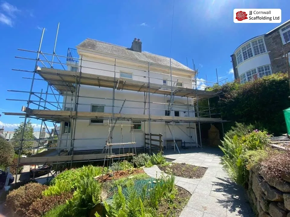 Domestic scaffolding in Cornwall: white rendered house two lift scaffold over a planted garden