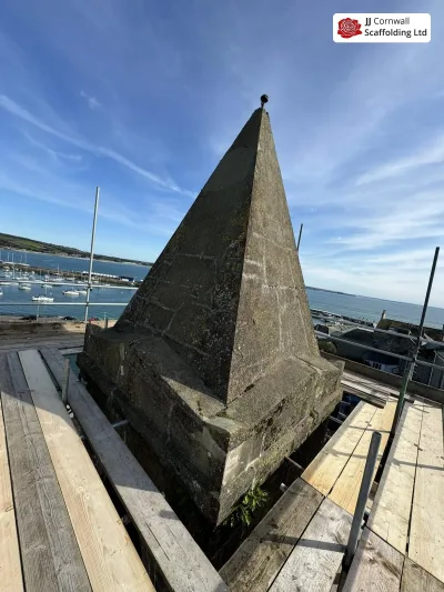 Free-standing buttressed scaffold beside a historic Cornish structure
