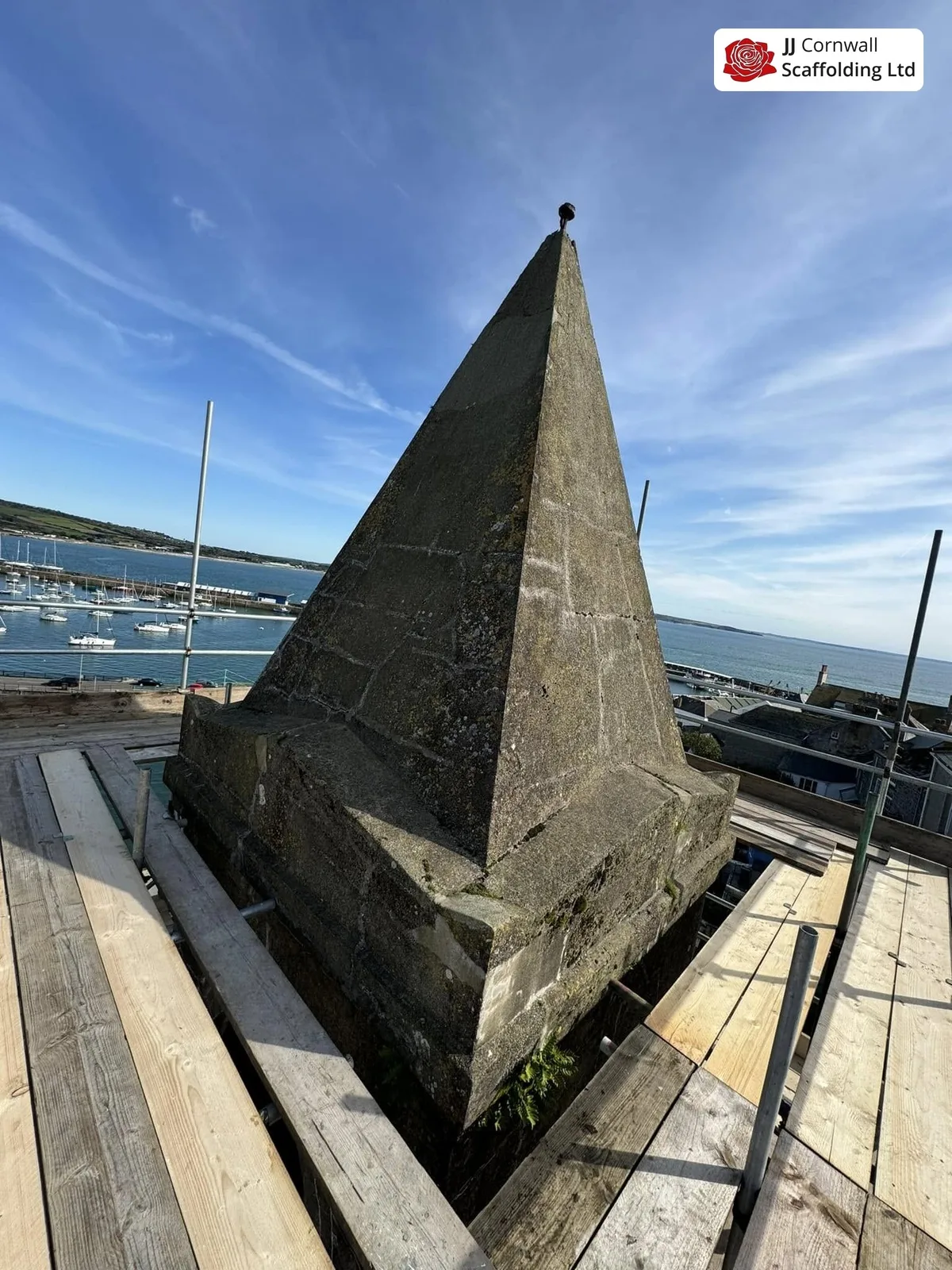 Free-standing buttressed scaffold beside a historic Cornish structure