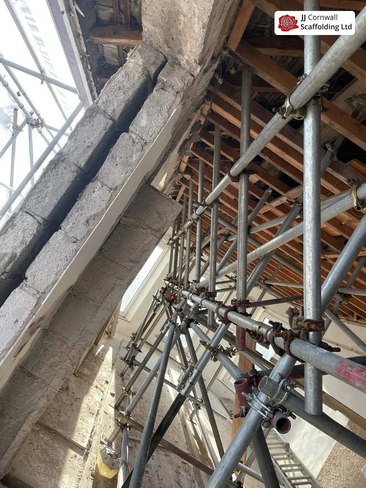 Heritage scaffolding in Cornwall: internal birdcage against granite with roof timbers above