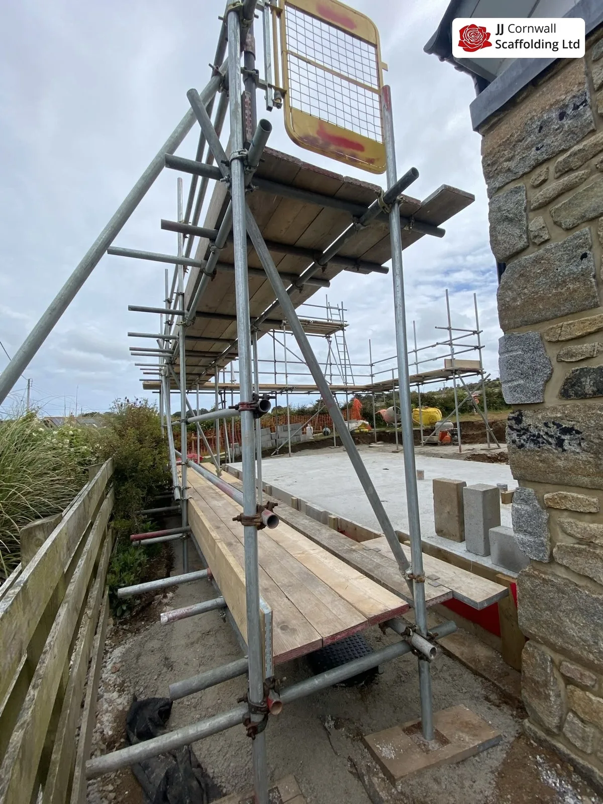 Scaffold hire in Cornwall: safe access boarded deck and guardrail against a granite wall